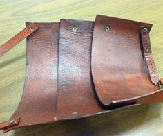 three pieces of brown leather sitting on top of a wooden table next to each other