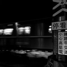 black and white photograph of a train passing by in the night with chinese writing on it