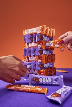 two hands reaching for candy bars stacked on top of each other, with one hand grabbing them