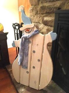 a wooden sleigh with a snowman on it in front of a fireplace