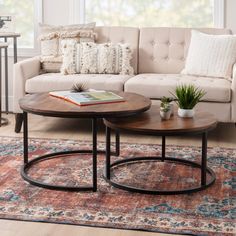 two coffee tables sitting on top of a rug in front of a couch