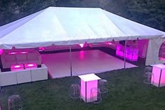 a large tent set up with pink lights on the floor and stools under it