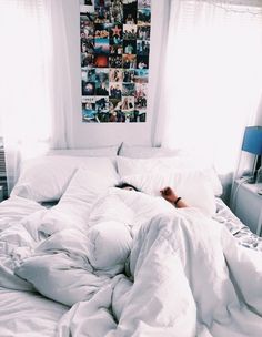 an unmade bed with white sheets and blankets on it in front of a window