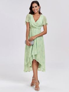 a woman in a green dress posing for the camera with her hand on her hip