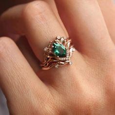 a woman's hand with a green ring on top of her finger and an emerald stone in the middle