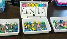 three white trays filled with small toy animals and letters that spell out the word addition center