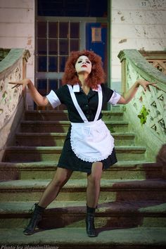 a woman with red hair is standing on the steps in front of some stairs and holding her arms out