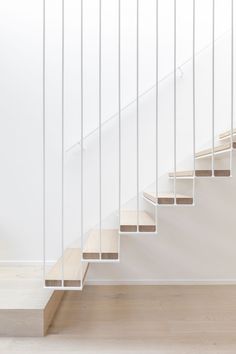 a white staircase with wooden handrails in an empty room