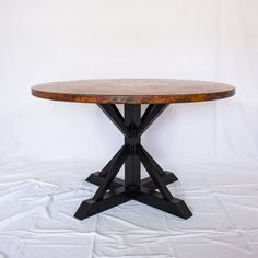 a round wooden table sitting on top of a white sheet