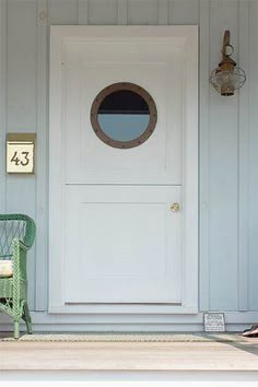 a green chair sitting in front of a white door with a round window on it