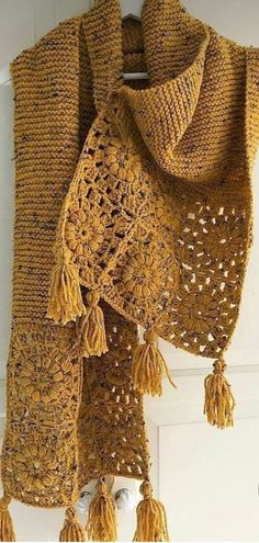 a crocheted shawl hanging on a door with tassels around it