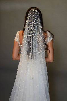 the back of a woman's wedding dress with beaded veil on her head