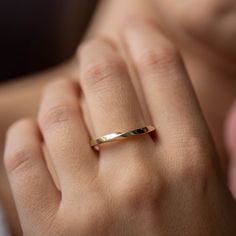 a woman's hand with a gold ring on her finger and the other hand holding it