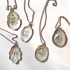 three silver necklaces with different designs and words on them, all hanging from chains