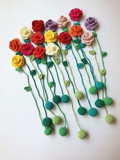 crocheted flowers are arranged in rows on a white surface