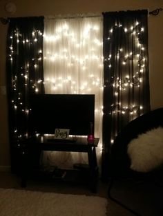 a living room with lights on the curtains and a tv in front of a window