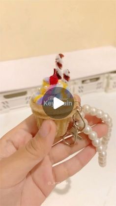 a person is holding an ice cream cone keychain in their left hand and there are other items on top of it