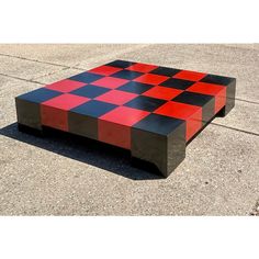 an unusual coffee table made out of wood and painted red, black and grey squares