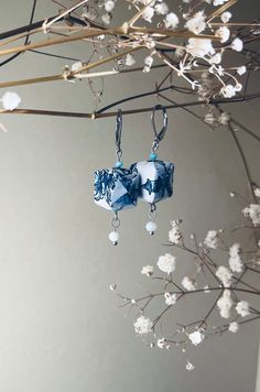 two blue and white glass beads hanging from a branch with flowers in the foreground