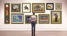 a person standing in front of a wall with many paintings on it and looking at them