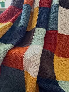 a crocheted blanket with multicolored squares on the top and bottom, draped over a window sill