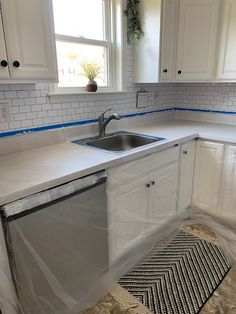 a kitchen that has been painted white with blue tape on the counter tops and cabinets