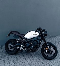 a white and black motorcycle parked next to a wall