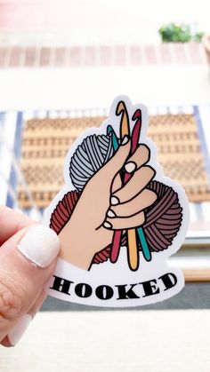 someone holding up a sticker that says hooked