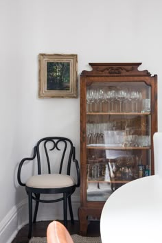 a chair sitting in front of a cabinet filled with wine glasses