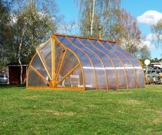 a green house sitting on top of a lush green field