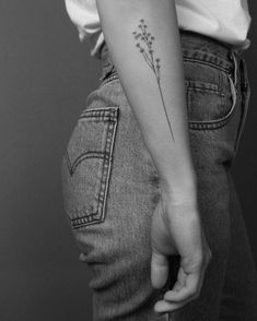 a woman's arm with a small flower tattoo on it