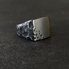 Black Zirconium Meteor Shower Ring. Designed and carved to look like it was forged through an intense Meteor shower. Black Zirconium is the only metal that can be treated to turn black and the most durable option when it comes to creating a black ring. This ring is hand-carved from a solid block of metal. Clients have various options in terms of width and finger size. Clients also have the opportunity to either have the top black or silver in color. Manufacturing time of these rings can take up Modern Black Engraved Rings, Black Oxidized Metal Rings, Unique Black Oxidized Finish Ring, Unique Black Ring With Oxidized Finish, Black Brutalist Sterling Silver Jewelry, Black Brutalist Jewelry As A Gift, Minimalist Hand Forged Black Rings, Modern Hand Forged Black Rings, Mount Doom