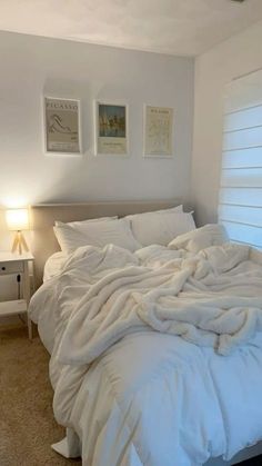 an unmade bed with white sheets and pillows