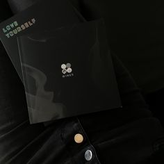 a person holding two black folders with white flowers on them and the words love yourself written in green