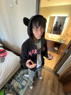 a young boy wearing a black bear hoodie standing in front of a bedroom mirror