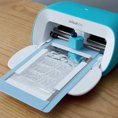 a blue and white cricut joy machine on a wooden table with the screen open