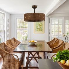 a dining room table with chairs and a bowl of fruit on top of the table