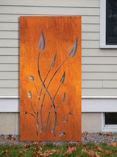 a painting on the side of a house that is orange and grey with silver leaves