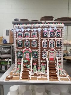 a large gingerbread house with lights on it's side in a kitchen area