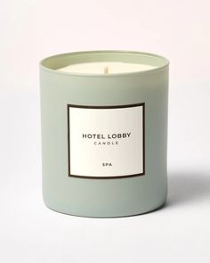 a candle with a label on it sitting in front of a white background that says hotel lobby