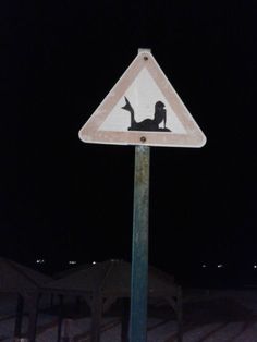 a street sign with a silhouette of a person laying on the ground at night time