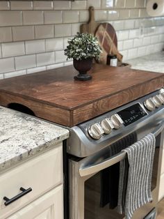 a potted plant sitting on top of a wooden cutting board next to an oven