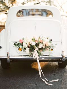 an old white car with flowers tied to it