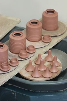 several clay vases and bowls sitting on plates