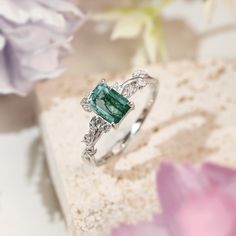 Connect with the grounding energy of the Earth Moss Agate Ring, inspired by the element of earth. This piece showcases an emerald-cut moss agate center stone, symbolizing growth and harmony with nature. The intricate leaves surrounding it, adorned with shining white topaz, pay homage to the natural beauty and tranquility of the earth. Wear this ring as a reminder to stay rooted, find balance, and celebrate the beauty of the natural world. ✦ 14K white gold vermeil (14K white gold plated over a st Nature-inspired Rings With May Birthstone Gemstone, Nature-inspired Gemstone Rings For May Birthstone, Nature-inspired Rings With May Birthstone, Nature-inspired Emerald Ring For May Birthstone Gift, Gift Nature-inspired Emerald Ring For May Birthstone, Emerald Rings With Natural Stones For May Birthstone, Emerald Cut Tourmaline Ring Gift, Luxury Emerald Cut Emerald Ring With Gemstone Accents, Emerald Cut Emerald Ring With Gemstone Accents