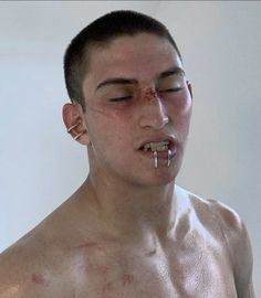 a shirtless man with piercings on his nose