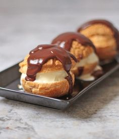 chocolate covered donuts sitting on top of a black plate with white frosting and drizzled