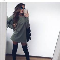 a woman taking a selfie in front of a mirror wearing thigh high boots and holding a cell phone