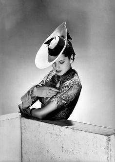 black and white photograph of a woman wearing a hat with her hands on her chest