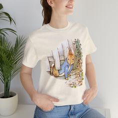 Stylish cute Beatrix Potter classic story book character t-shirt. This classic unisex jersey short sleeve tee fits like a well-loved favorite. Soft cotton and quality print make users fall in love with it over and over again. These t-shirts have-ribbed knit collars to bolster shaping. The shoulders have taping for better fit over time. Dual side seams hold the garment's shape for longer.  .: 100% Airlume combed and ringspun cotton (fiber content may vary for different colors) .: Light fabric (4. Themed Cartoon Print Crew Neck T-shirt, Themed Short Sleeve T-shirt With Cartoon Print, Themed Pre-shrunk Cotton T-shirt, Themed Cotton Crew Neck T-shirt, Themed Pre-shrunk Short Sleeve T-shirt, Themed Short Sleeve Pre-shrunk T-shirt, Book Character, Story Book, Beatrix Potter